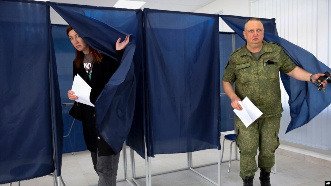A woman and a serviceman leave a voting area at a polling station during Russia-organized elections in Donetsk, capital of Ukraine's mostly Russian-occupied Donetsk region, Sept. 10, 2023. 