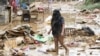 A resident walks amongst debris of destroyed belongings next to her house at a village in Manila on July 25, 2024, a day after heavy rains fueled by Typhoon Gaemi and the seasonal monsoon lashed Manila and surrounding regions.
