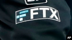 FILE - The FTX logo appears on home plate umpire Jansen Visconti's jacket at a baseball game with the Minnesota Twins on Sept. 27, 2022, in Minneapolis. 