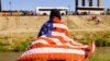 Yon migran ki soti Venezyela ke Etazini ekspilse epi voye tounen Meksik anba Tit 42, kenbe yon drapo Ameriken pandan li kanpe bo kote rivye Bravo a nan Ciudad Juarez, Meksik, 26 Oktob, 2022. 