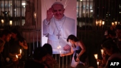 People place lit candles close to a picture of Pope Francis during a vigil to pray for his health in Buenos Aires on March 7, 2025.
