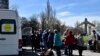 People wait to board a bus during their evacuation, with a MiG-17 fighter jet monument in the background, in Kramatorsk, Ukraine, April 9, 2022.