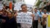 FILE - Political dissident Nguyen Quang A (C) holds a sign which reads "Formasa - damaged the environment and is a criminal" during a protest in Hanoi, Vietnam, May 1, 2016.