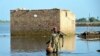 FILE - A man carries some belongings as he wades through floodwaters in Jaffarabad, a flood-hit district of Baluchistan province, Pakistan, Sept. 19, 2022. 