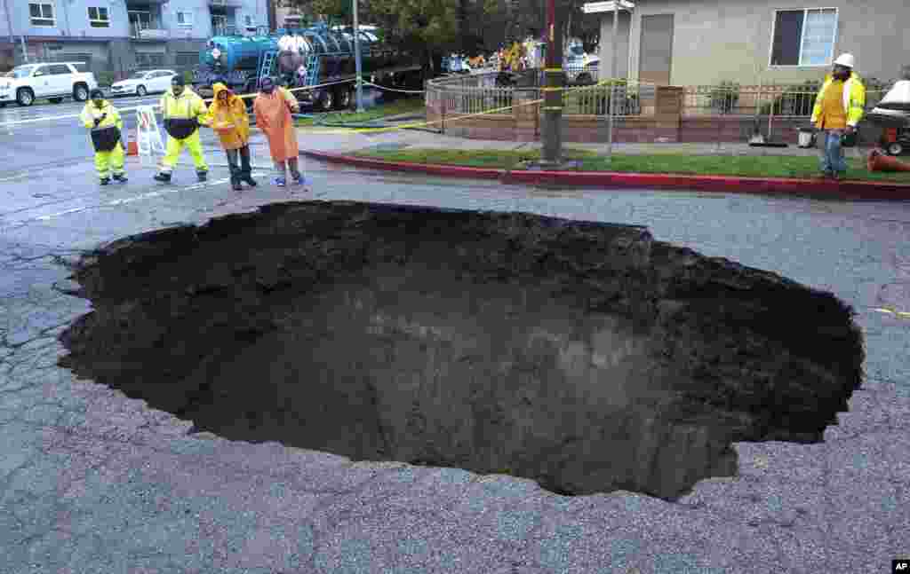 Inspectors examine a sinkhole in Studio City, north of Los Angeles, Feb. 18, 2017.&nbsp;Two vehicles fell into the 20-foot sinkhole on Friday night and firefighters rescued one woman who escaped her car but was found standing on her overturned vehicle.&nbsp;