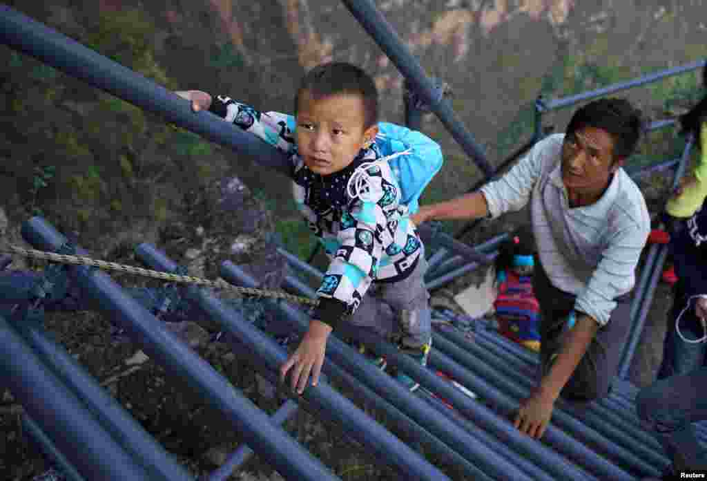 A student from "the cliff village" in Atule'er climbs newly-constructed steel ladders after school to go home for holidays, in Liangshan Sichuan province, China.