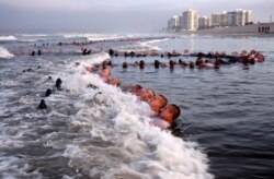 This May 4, 2020, photo provided by the U.S. Navy shows SEAL candidates participating in "surf immersion" during Basic Underwater Demolition/SEAL training at the Naval Special Warfare Center in Coronado, Calif.