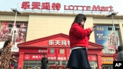 一名女子走在中国北京乐天超市前(2017年3月17日)