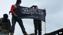 FILE - Rebels from al-Qaida-affiliated Jabhat al-Nusra wave their brigade flag as they stand atop a Syrian air force helicopter at Taftanaz air base, Jan. 11, 2013.