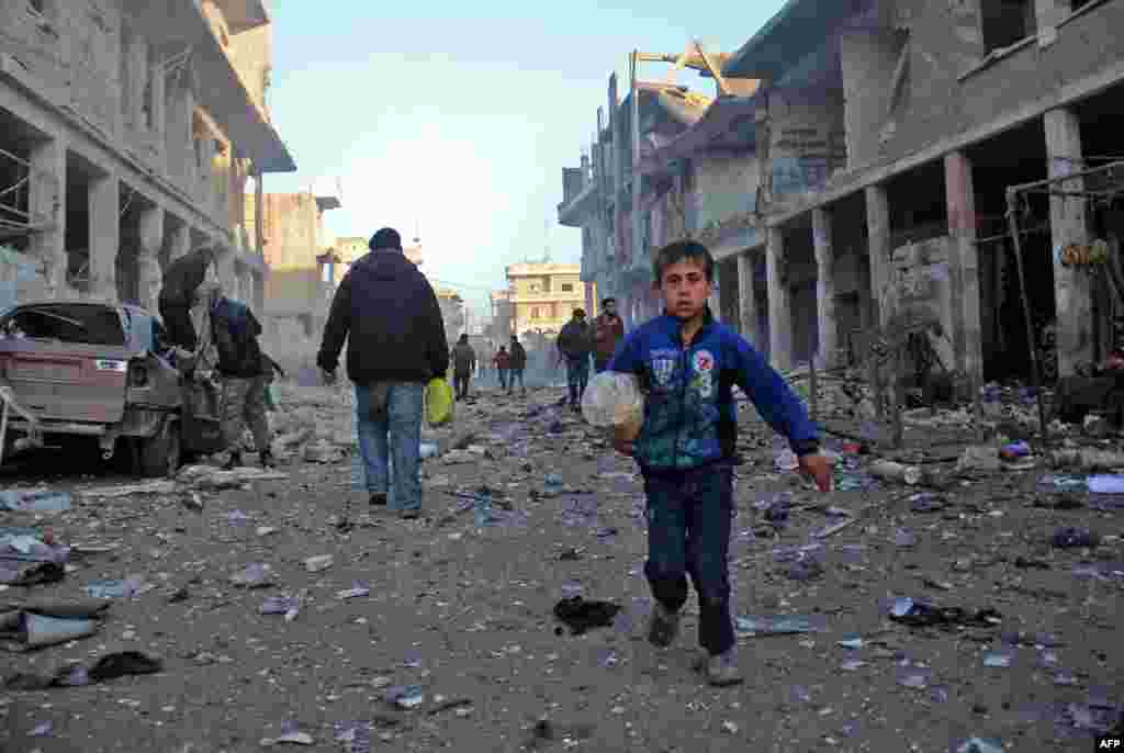 A Syrian boy runs while carrying bread following a reported airstrike by government forces, in the Syrian town of Binnish, on the outskirts of Idlib.