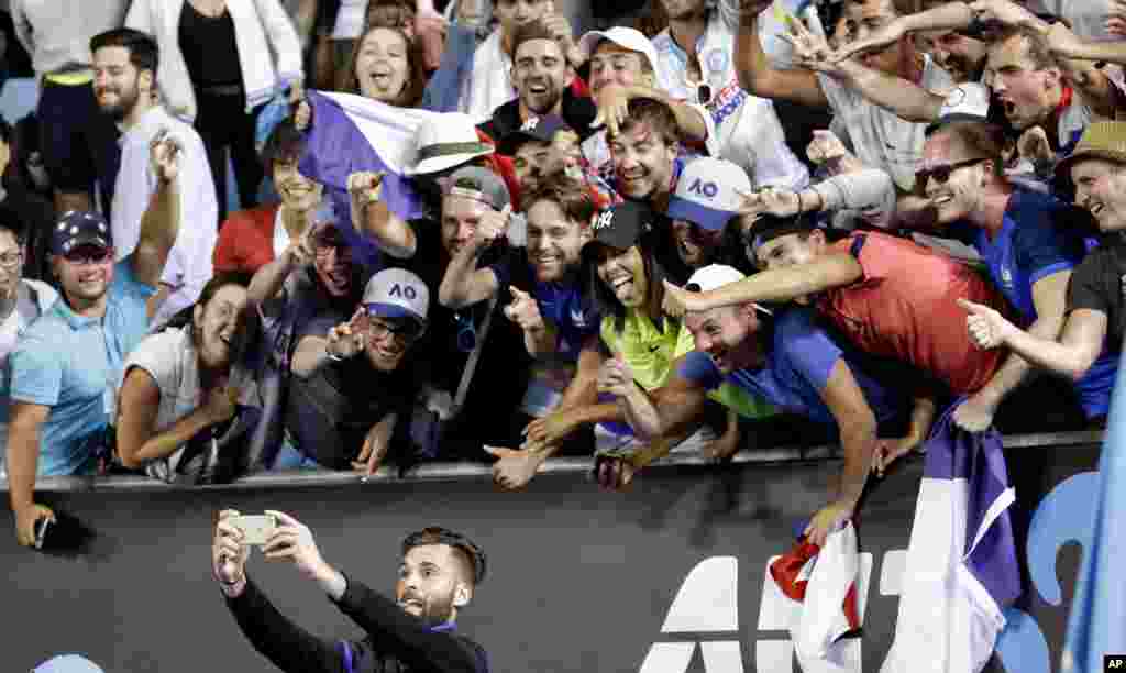 France's Benoit Paire takes selfie with his supporters as he celebrates after defeating Italy's Fabio Fognini in their second round match at the Australian Open tennis championships in Melbourne, Australia.
