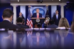 FILE - President Donald Trump speaks, flanked by White House economic advisor Larry Kudlow and Treasury Secretary Steven Mnuchin, during a briefing on the U.S. economy at the White House in Washington, July 2, 2020.