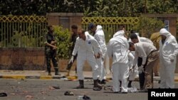 Forensic policemen inspect the site of a suicide bomb attack at a parade square in Sanaa, Yemen, May 21, 2012. 