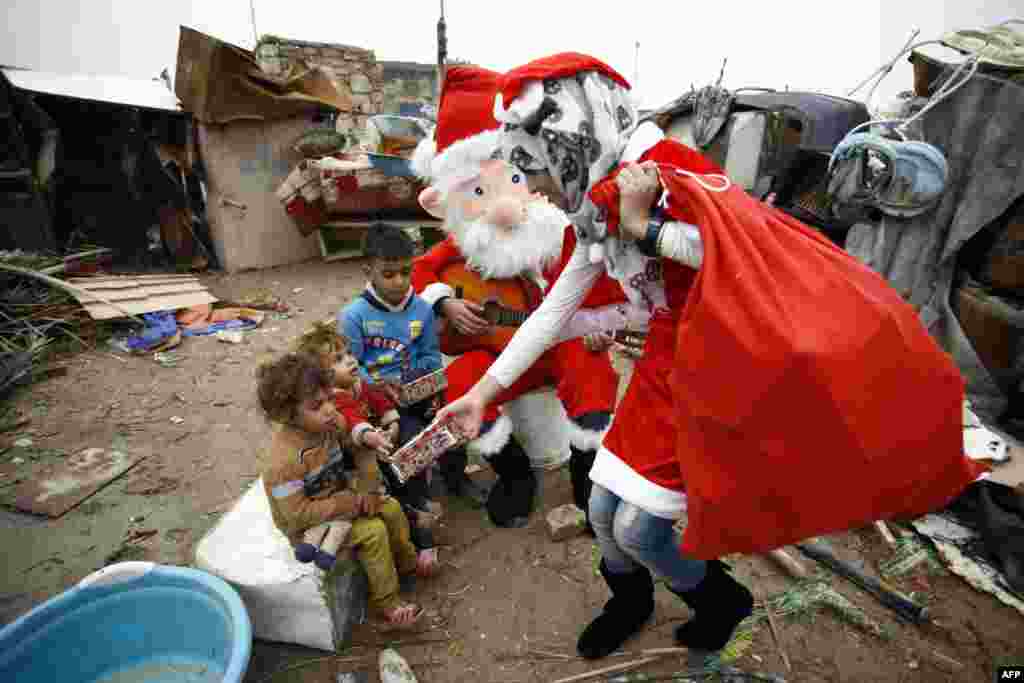 An Iraqi student dressed in a Santa Claus outfit distribute gifts to impoverished children outside their shanty home in the Shi'ite city of Najaf.