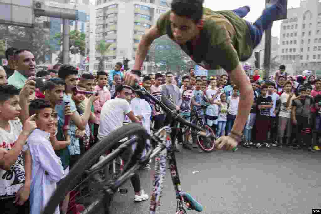 A young Egyptian man turns in the air as a part of bicycle acrobatic show after Eid Al-Fitr prayers at Mostafa Mahmoud square in Cairo, Egypt, June 25, 2017. (H. Elrasam/VOA)
