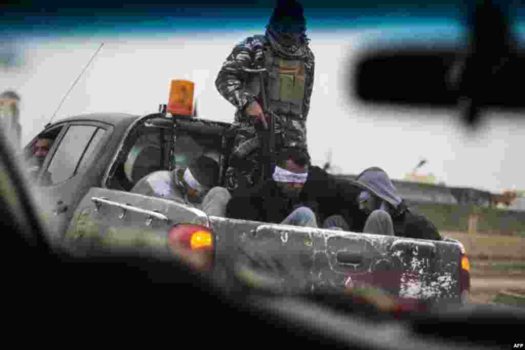 Christian militia fighters from the Nineveh Plain Protection Units (NPU) drive a pick-up truck in Qaraqosh (also known as Hamdaniya), transporting four men, allegedly members of the Islamic State (IS) group that were found inside a tunnel in Mosul, Iraq.