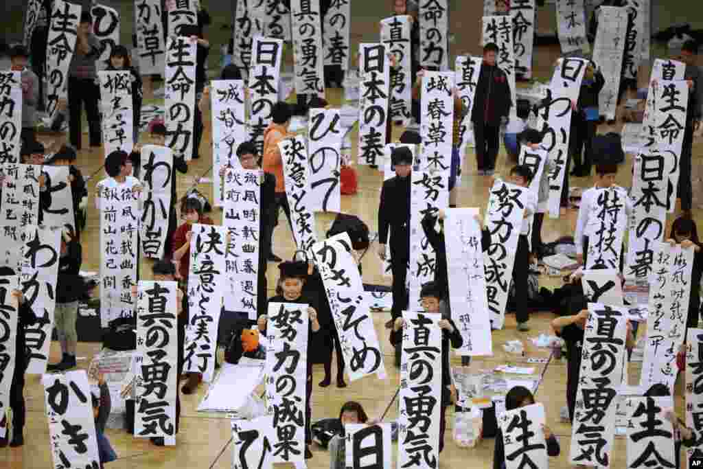 Participants show off their traditional Japanese calligraphy works during the annual New Year's calligraphy contest at the Budokan martial arts hall in Tokyo.