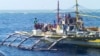 FILE - In this photo provided by Renato Etac, Chinese Coast Guard members, wearing black caps and orange life vests, approach Filipino fishermen as they confront them off Scarborough Shoal in the South China Sea.