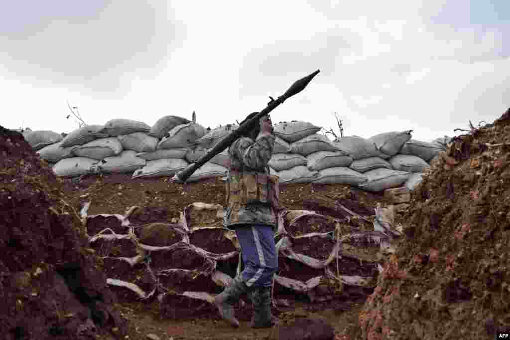 An opposition fighter from the Sham brigade walks holding a rocket-propelled grenade in a trench on the front line during the ongoing clashes with Syrian government forces in the village of Teir Maalah in Homs province of Homs.