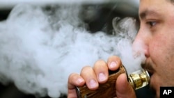 A man breathes vape from an e-cigarette at a vape shop in London, Aug. 17, 2018.