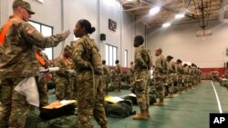 FILE - In this image provided by the U.S. Army, recent basic combat training graduates have their temperatures taken as they arrive at Fort Lee, Va, on March 31, 2020, after being transported using sterilized buses from Fort Jackson, S.C.