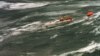 FILE - The injured crew of demasted Australian yacht "Stand Aside" await rescue by helicopter as they tow a life-raft in Bass Strait during the Sydney-to-Hobart ocean race, Dec. 27, 1998.