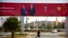 A woman crosses the street near a billboard commemorating the state visit of Chinese President Xi Jinping in Port Moresby, Papua New Guinea, Nov. 15, 2018.