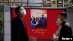 上海街头戴着口罩的行人走过宣传习近平的宣传画。（2020年3月23日）