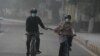 Warga tampak mengenakan masker saat bersepeda di jalanan Kota Lahore, Pakistan, pada 3 November 2024. (Foto: AP/K. M. Chaudary)