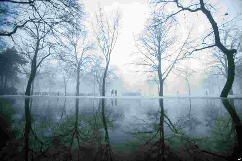 Strollers walk during morning fog at the City Park of Budapest, Hungary.