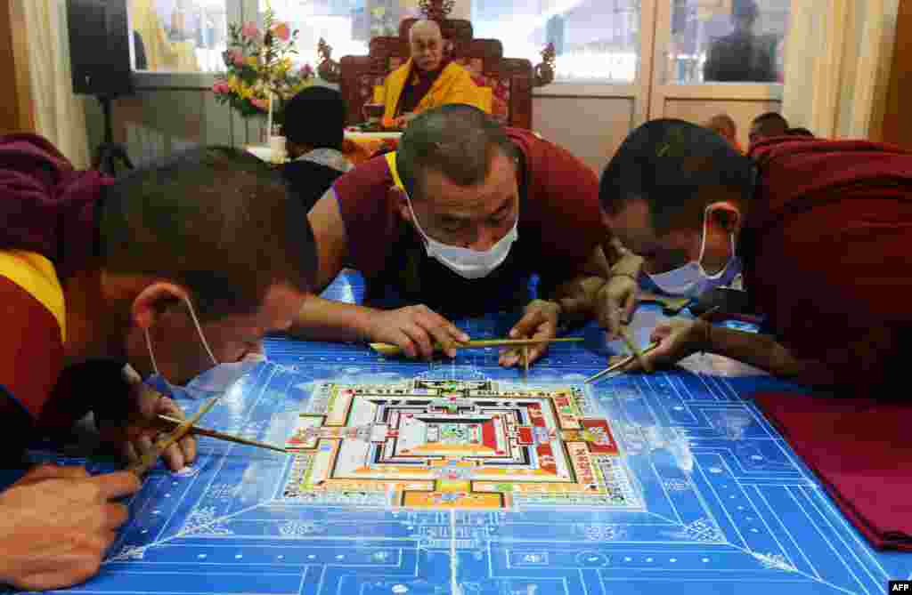 Tibetan Spiritual Leader The Dalai Lama looks on as Tibetan Buddhist monks work on a traditional painting during a special religious prayer at Bodhgaya, India.