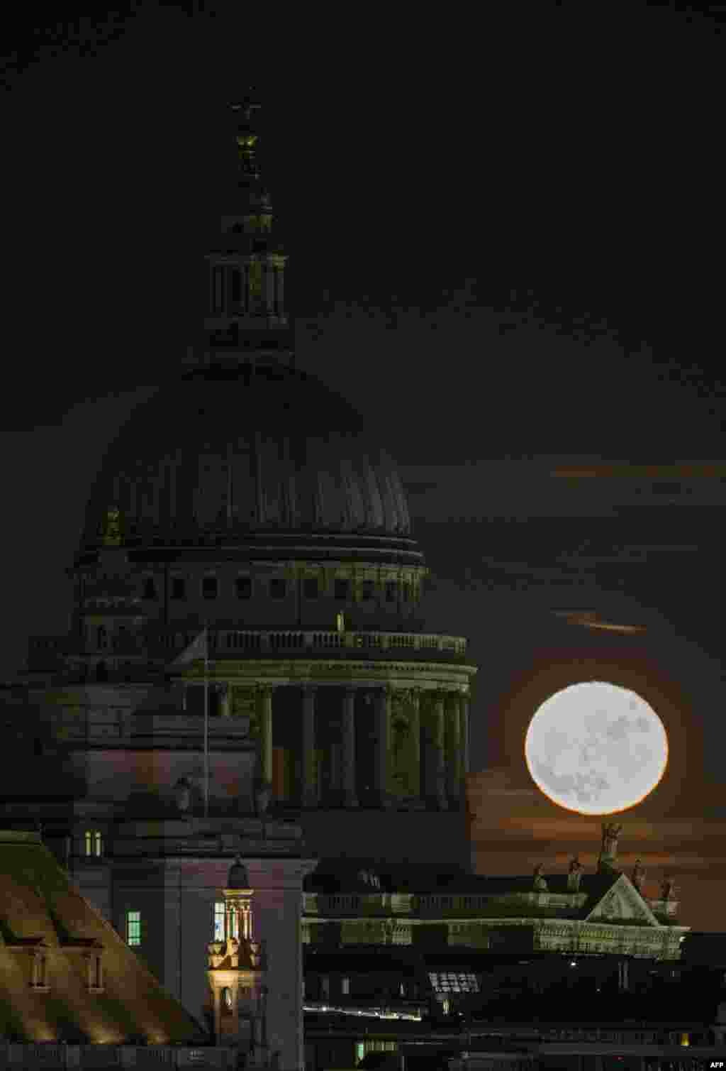 A supermoon rises on the horizon beyond St. Paul's Cathedral in central London.