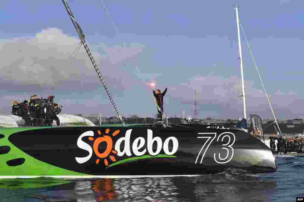 French skipper Thomas Coville (C) holds a burning flare onboard his "Sodebo Ultim'" multihull as he arrives in the port of Brest, western France, after beating the record in solo non-stop round the world sailing. Coville, 48, slashed eight days off the record when he ended an astonishing solo non-stop circumnavigation of the World on his 31m maxi trimaran on Dec. 25, 2016, in just 49 days, 3 hours, 7mins and 38secs.