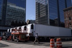 A worker walks past freezer trucks to store cadavers, part of a makeshift morgue behind a hospital, during the outbreak of the coronavirus disease, in the Manhattan borough of New York City, New York, March 26, 2020.