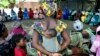 FILE - A mother carrying an infant on her back attends a meeting of women from several communities eradicating female genital mutilation, in Diabougo, Senegal.