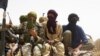 Fighters from Islamist group Ansar Dine stand guard during the handover of a Swiss female hostage for transport by helicopter to neighboring Burkina Faso, at a designated rendezvous point in the desert outside Timbuktu, Mali Tuesday, April 24, 2012. Two m