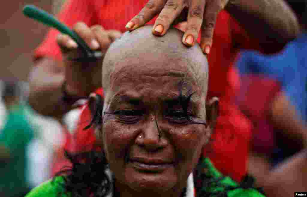 A supporter of Tamil Nadu Chief Minister Jayalalithaa Jayaraman gets her head shaved near Jayalalithaa's burial site in Chennai, India.