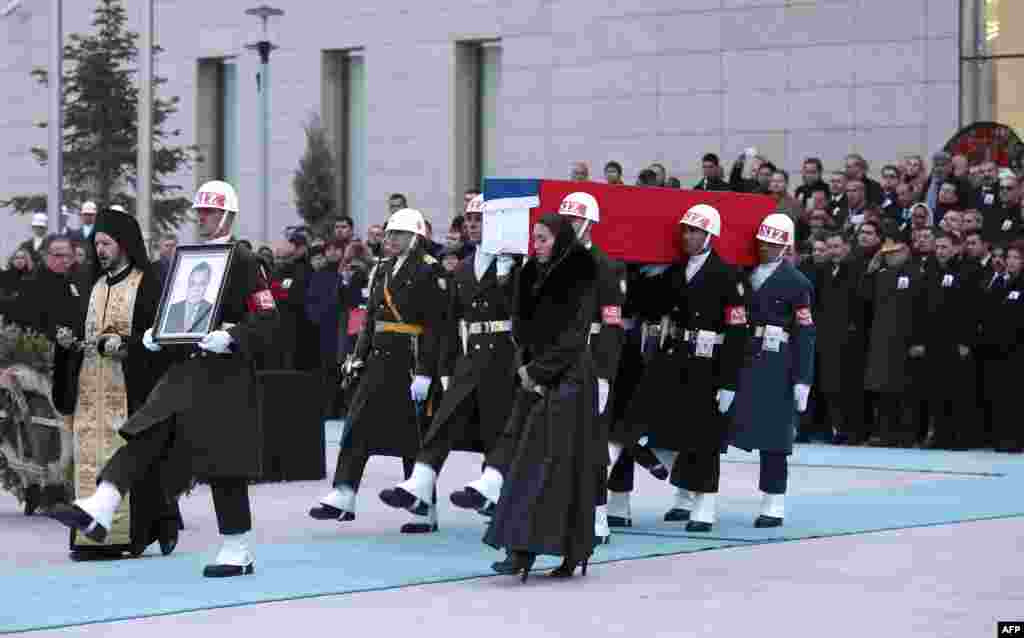 Members of a Turkish forces honor guard carry the Russian flag-draped coffin of late Russian Ambassador to Turkey Andrei Karlov and a picture of him during a ceremonial farewell with full state honors on the tarmac of Ankara's Esenboga Airport.
