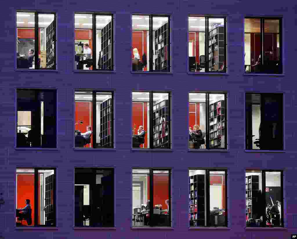 Employees are seen working through the windows of a big lawyer's office in central Frankfurt, Germany.