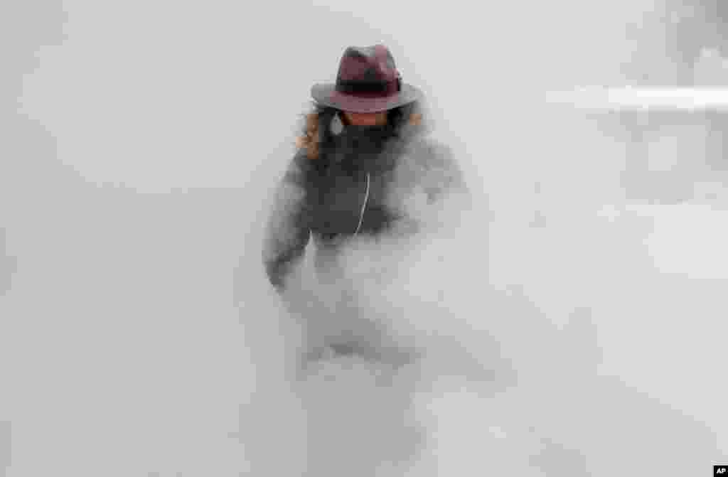 A woman walks through steam from an underground ventilation, as temperatures dropped below -20°C (- 4°F) in Bucharest, Romania.