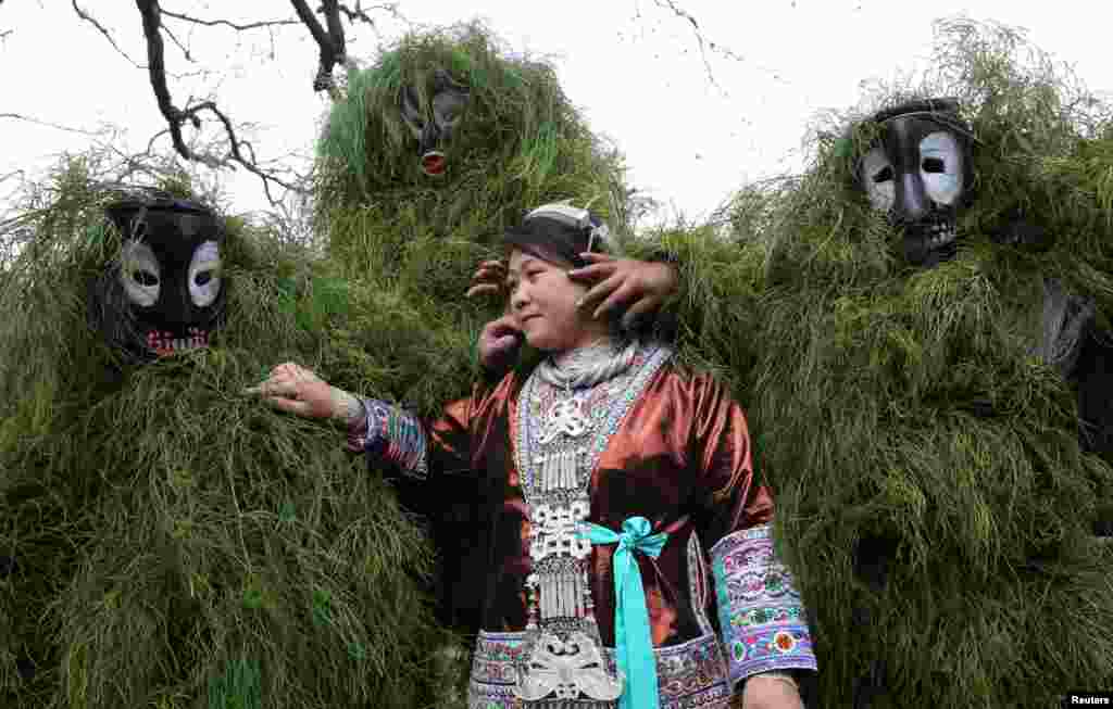 Ethnic Miao men wearing traditional masks smear dust on a woman's face to wish her good luck during a local celebration event for Lunar New Year in Liuzhou, Guangxi Zhuang Autonomous Region, China, Feb. 5, 2017.