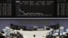Traders work at their desks in front of the DAX board at the Frankfurt stock exchange, May 14, 2012. 