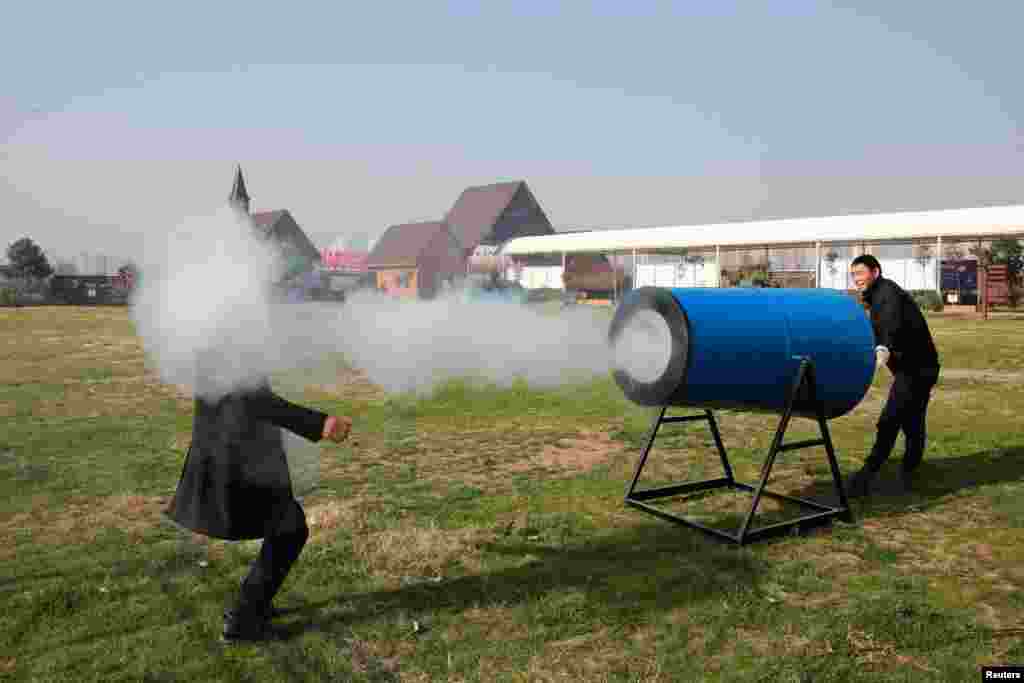 People demonstrate a home-made "smog cannon" which fires cannonballs made of "water and tobacco tar" to remind people the importance of protecting environment, in Xiangyang, Hubei province, China.