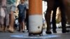 Shoppers walk past a bollard painted to represent a cigarette butt to raise awareness about new no smoking zones in Sydney, Sept. 26, 2016. A new program designed for indigenous Australians is helping lower their high rates of smoking.