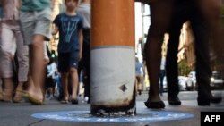 Shoppers walk past a bollard painted to represent a cigarette butt to raise awareness about new no smoking zones in Sydney, Sept. 26, 2016. A new program designed for indigenous Australians is helping lower their high rates of smoking.