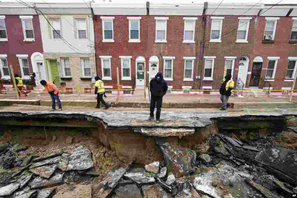 Workers inspect a sinkhole in Philadelphia, Pennsylvania. The Philadelphia Water Department said a water main break caused the sinkhole to open up on the street.