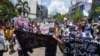 Protesters hold banners as they make the three-finger salute during a demonstration against the military coup in Yangon, Myanmar, May 12, 2021.