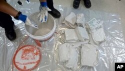 In this undated recent photo provided by the Australian Federal Police, an investigator removes packages of the methamphetamine drug from containers in Sydney. 