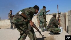 FILE - In this photo taken on Oct. 11, 2015, Syrian soldiers fire repelling an attack in Achan, Hama province, Syria.