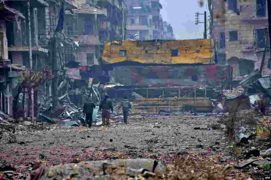 Syrian pro-government forces walk in Aleppo's Bustan al-Qasr neighborhood after they captured the area in the eastern part of the war torn city.